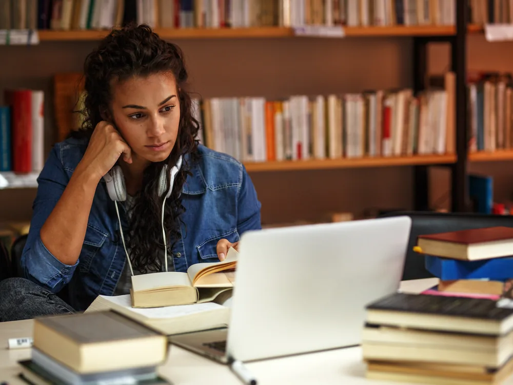 University student planning courses with books and a laptop